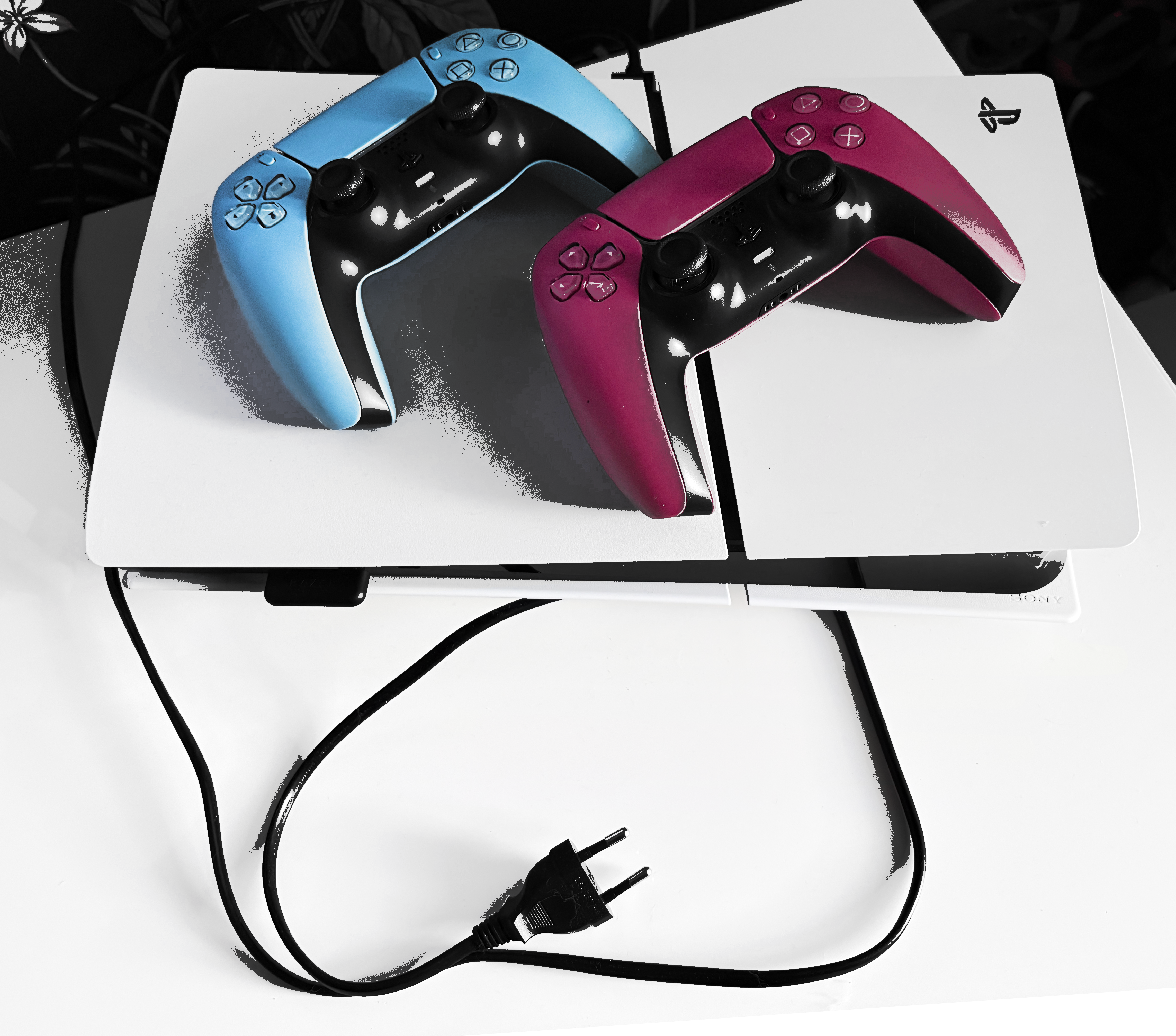 A picture of an unplugged PlayStation with two controllers in red and blue on top
